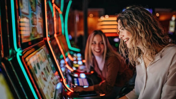 Girl friends gambling in casino on slot machinery