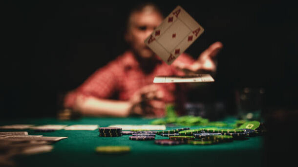 One mature man playing poker late by night, throwing playing cards on table.